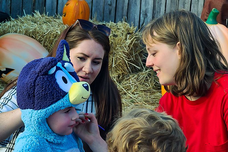 A volunteer painting a child's face at the Ohio Railway Museum's Pumpkin Patch Express